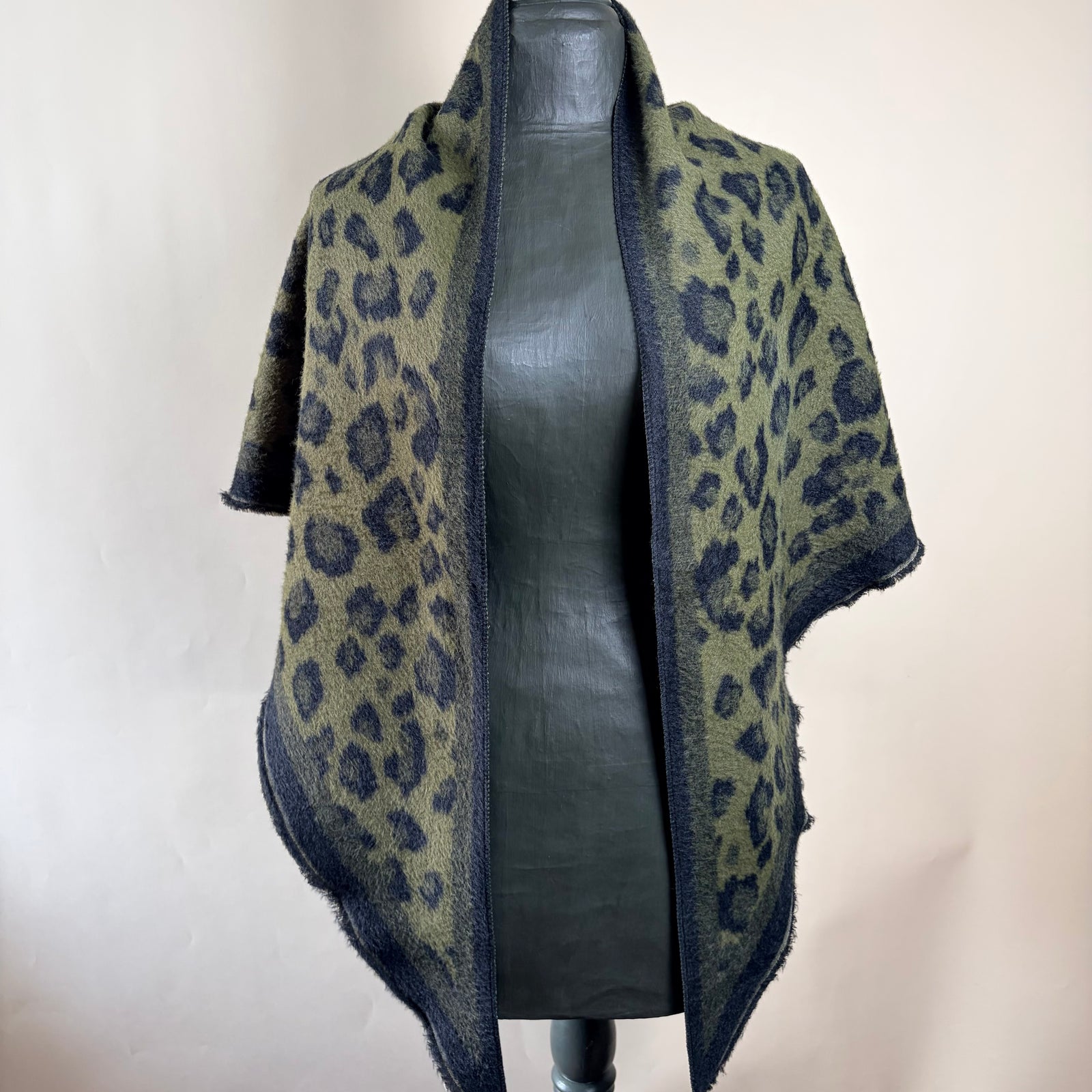 A dark blue and olive green patterned shawl with a textured, fuzzy knit, wrapped around a gray mannequin torso against a plain beige background.
