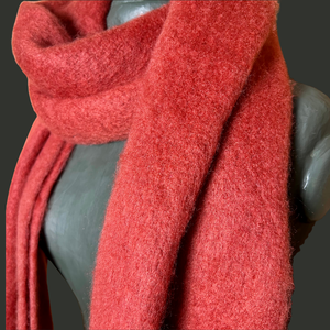 Close-up of a red scarf draped over a mannequin with a gray background
