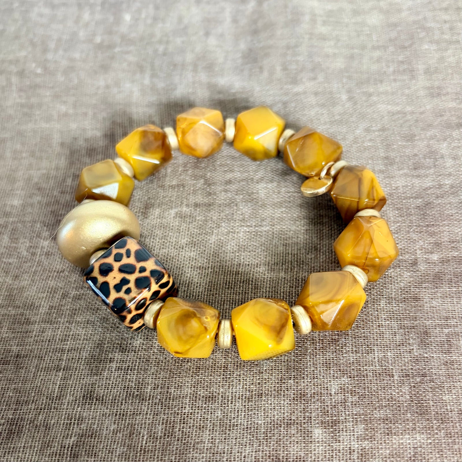 Bracelet with yellow beads and a leopard print bead on a textured gray background