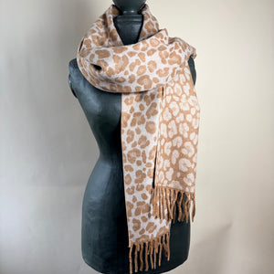 A leopard print scarf in beige and brown, draped on a black mannequin torso against a light beige background.