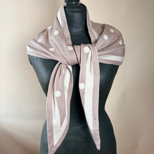 A dusty pink and cream striped scarf with white polka dots, styled on a black mannequin torso against a neutral beige background.