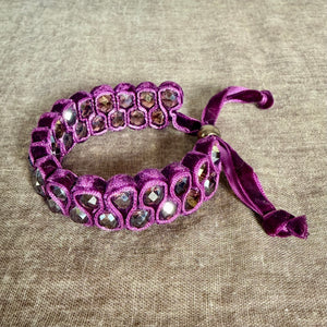 Purple bracelet with gemstone accents on a textured fabric background