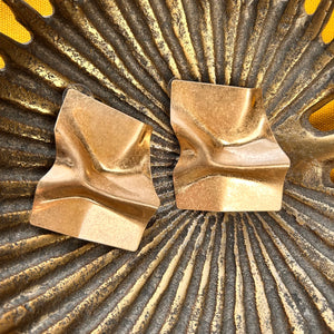 Gold earrings on a textured gold and black background